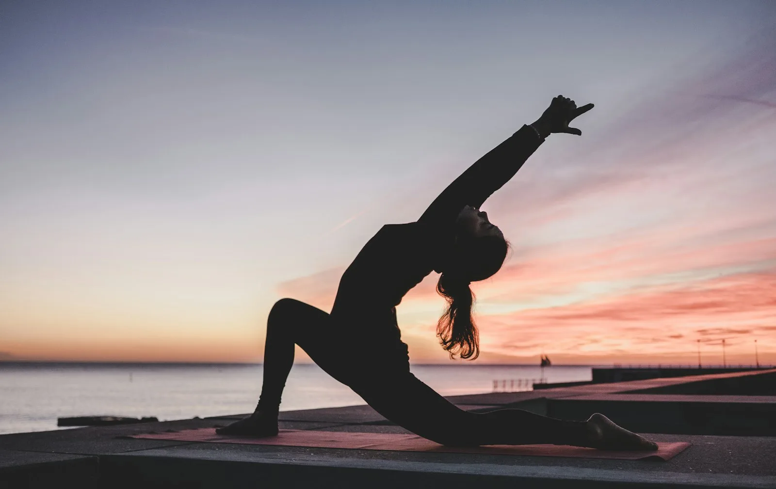 Person in einer ruhigen Yoga-Pose auf einer Matte